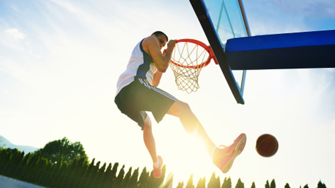 Street basketball player performing power slum dunk.