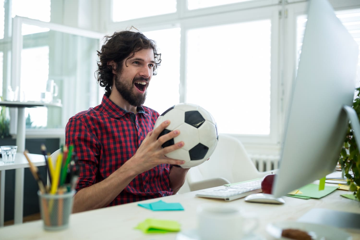 Male graphic designer cheering while watching football match Male graphic designer cheering while watching football match