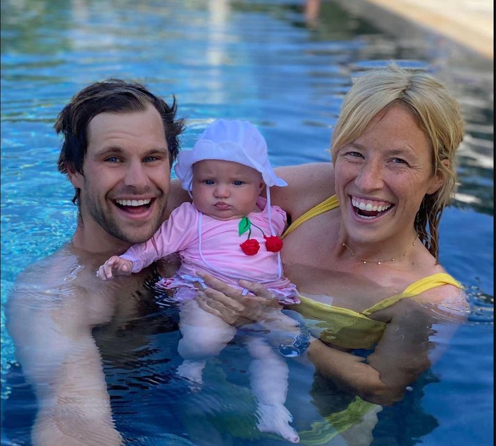 Thomas Detry and Sarah Taylor with their child in a swimming pool