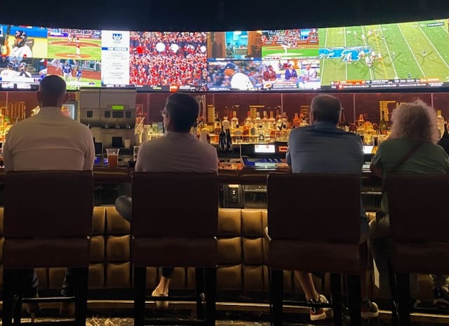 a group of people sitting at a bar watching tv a group of people sitting at a bar watching tv