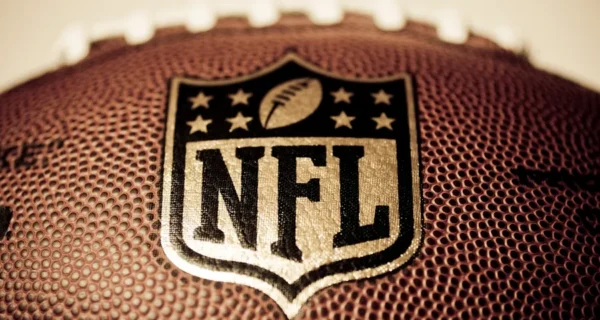 A cool close-up shot of a printed NFL logo on a brown football with a blurry background.