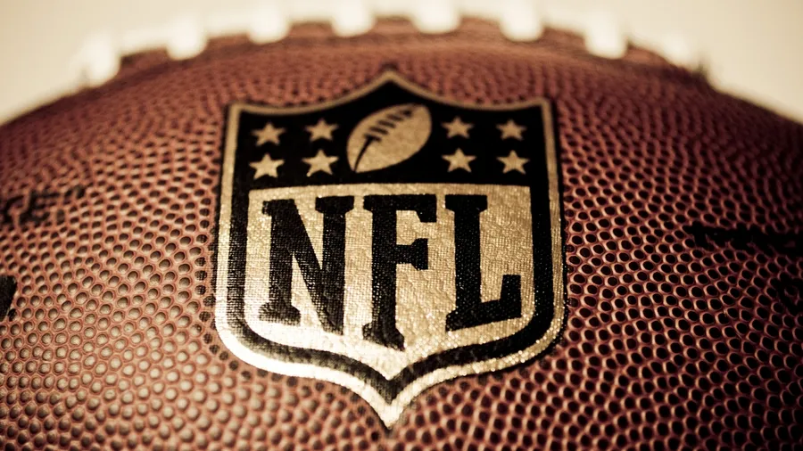 A cool close-up shot of a printed NFL logo on a brown football with a blurry background.