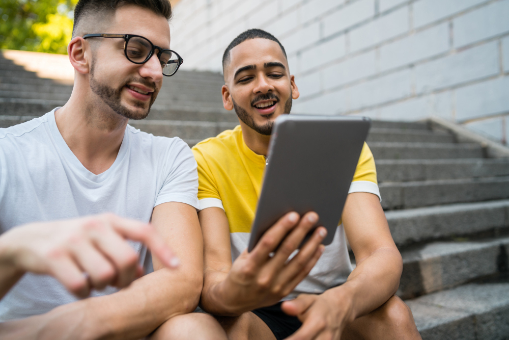 Portrait of happy gay couple spending time together and using a digital table