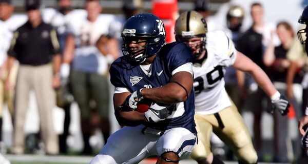 Football Player Hugging Ball While Opponent Chasing