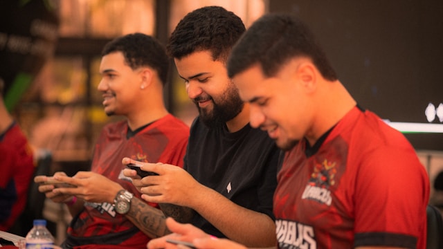 Three men playing mobile games together Three men playing mobile games together