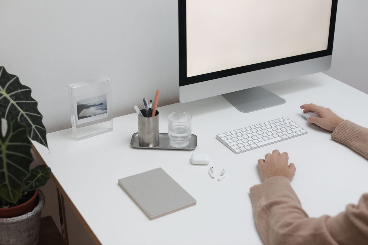 A clean and modern workspace featuring a desktop computer, keyboard, and minimal decor.