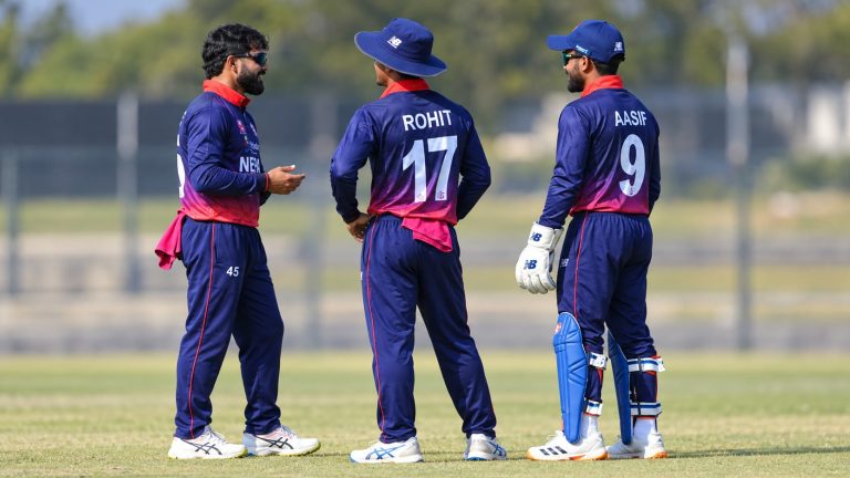 Nepal cricketers in navy, magenta and red uniforms confer on the outfield, with Rohit and Aasif’s jerseys visible.