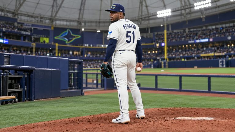 AI-generated editorial image of Freddy Peralta wearing Rays number 51 with a glove and baseball in a covered ballpark