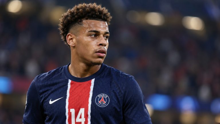 Désiré Doué wearing a navy Paris Saint-Germain shirt with a red central stripe.