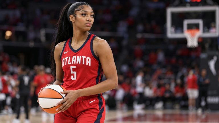 Angel Reese wearing a red Atlanta Dream No. 5 uniform and holding a basketball.