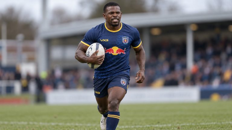 Christian Wade running with a rugby ball in Newcastle Red Bulls’ navy and yellow uniform.