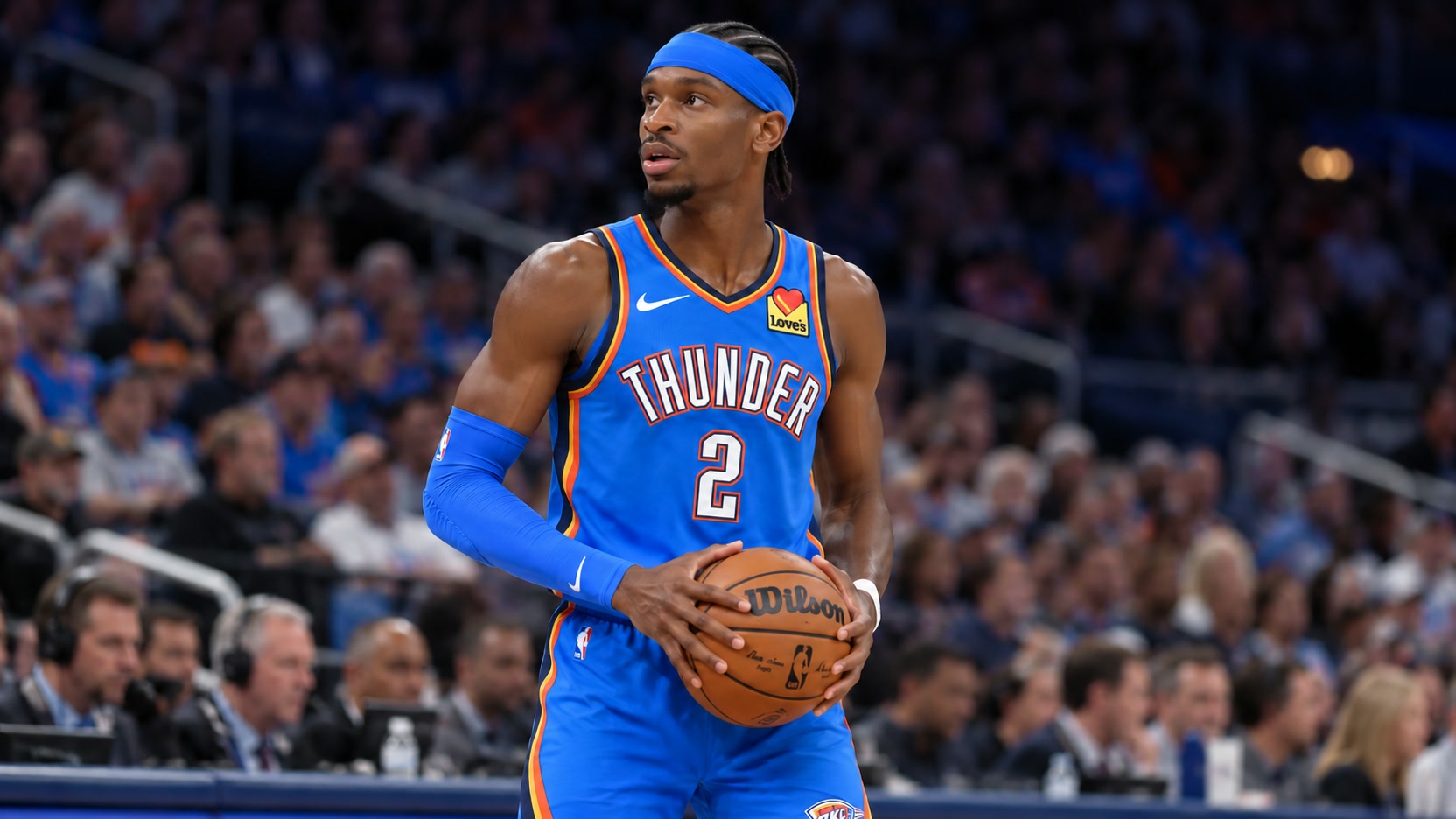 Shai Gilgeous-Alexander in Oklahoma City Thunder uniform Shai Gilgeous-Alexander in a blue Oklahoma City Thunder No. 2 uniform and blue headband holds a basketball at courtside.