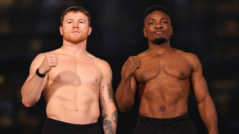 Canelo Alvarez and Christian Mbilli standing side by side in black trousers, each raising a fist in a pre-fight portrait.