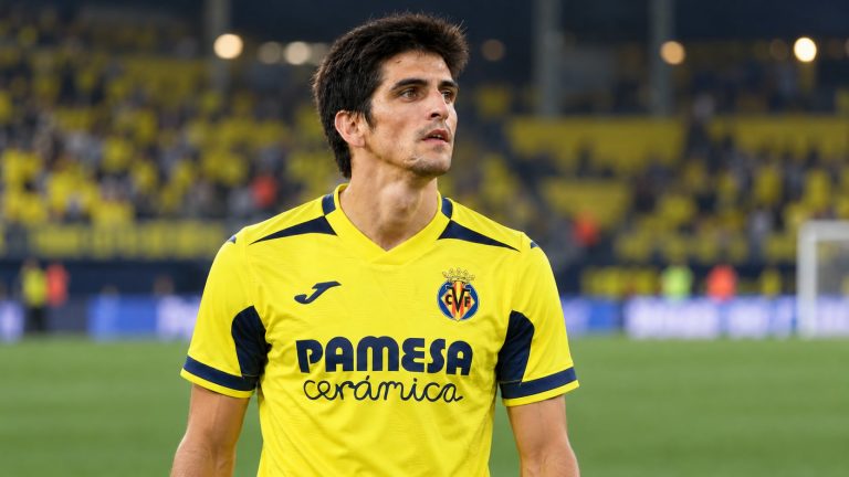 Gerard Moreno in Villarreal’s yellow home shirt with navy trim, the club crest and Pamesa Cerámica sponsor, beside a football pitch.